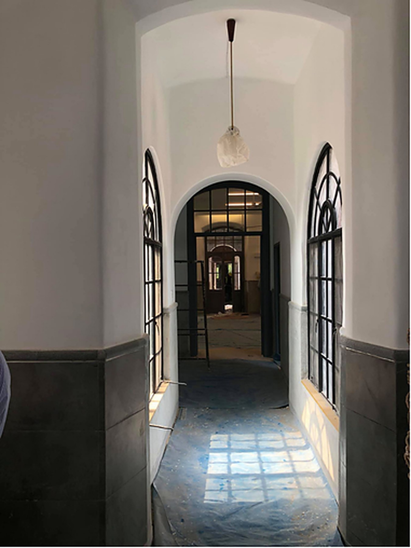 Restored corridor with arched windows and grey terrazzo floor at Mayo Hospital, Lahore